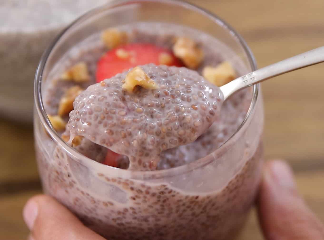 a teaspoon holding a chia pudding with strawberries and walnuts