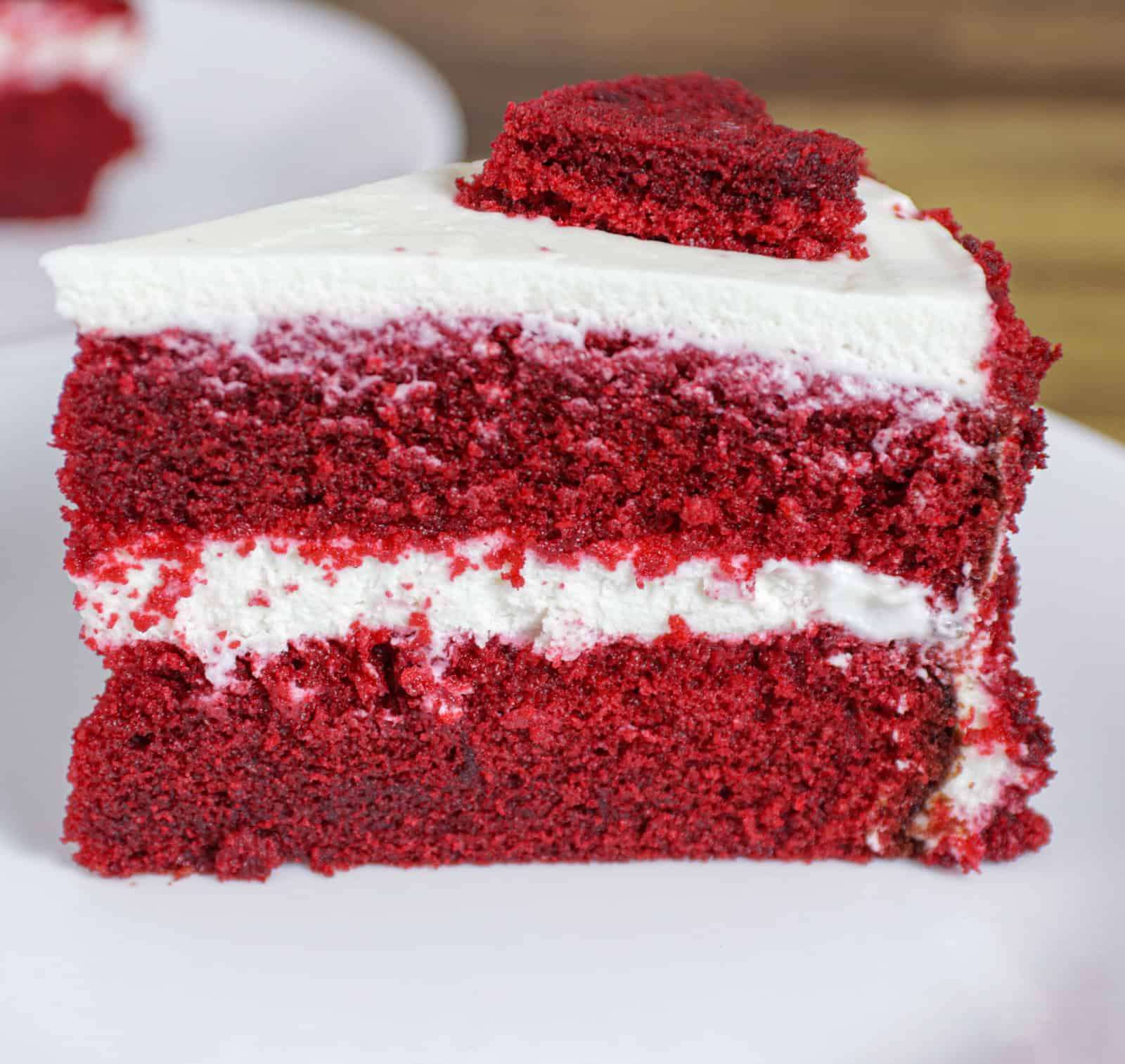 a close up on a moist red velvet cake with cream cheese frosting in between