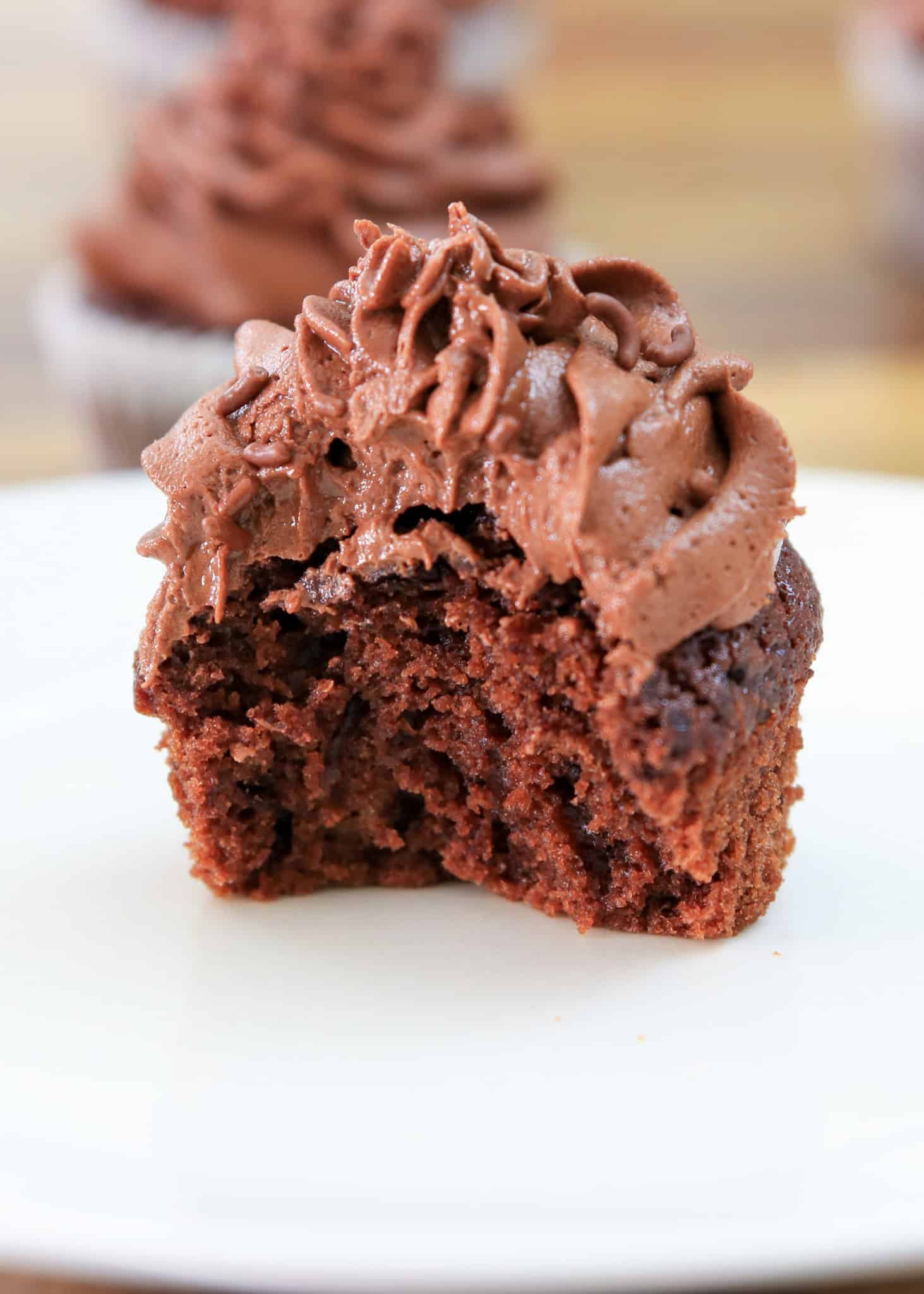 a bitten chocolate cupcake with chocolate butter cream frosting 