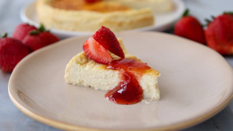 a slice of creamy and light high protein cottage cheese cheesecake topped with strawberry jam