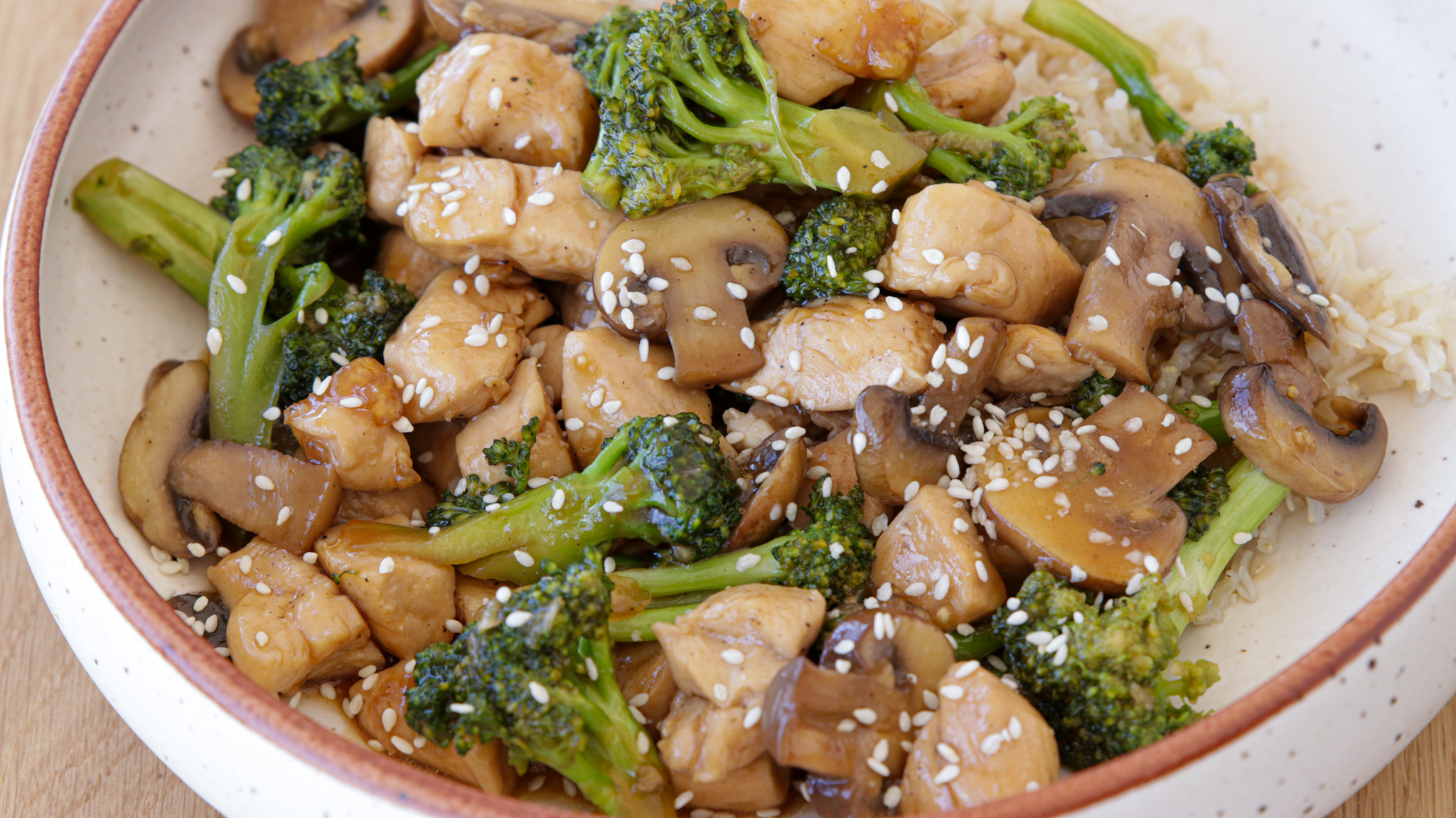 chicken broccoli stir fry with rice and sesame seeds on a large plate