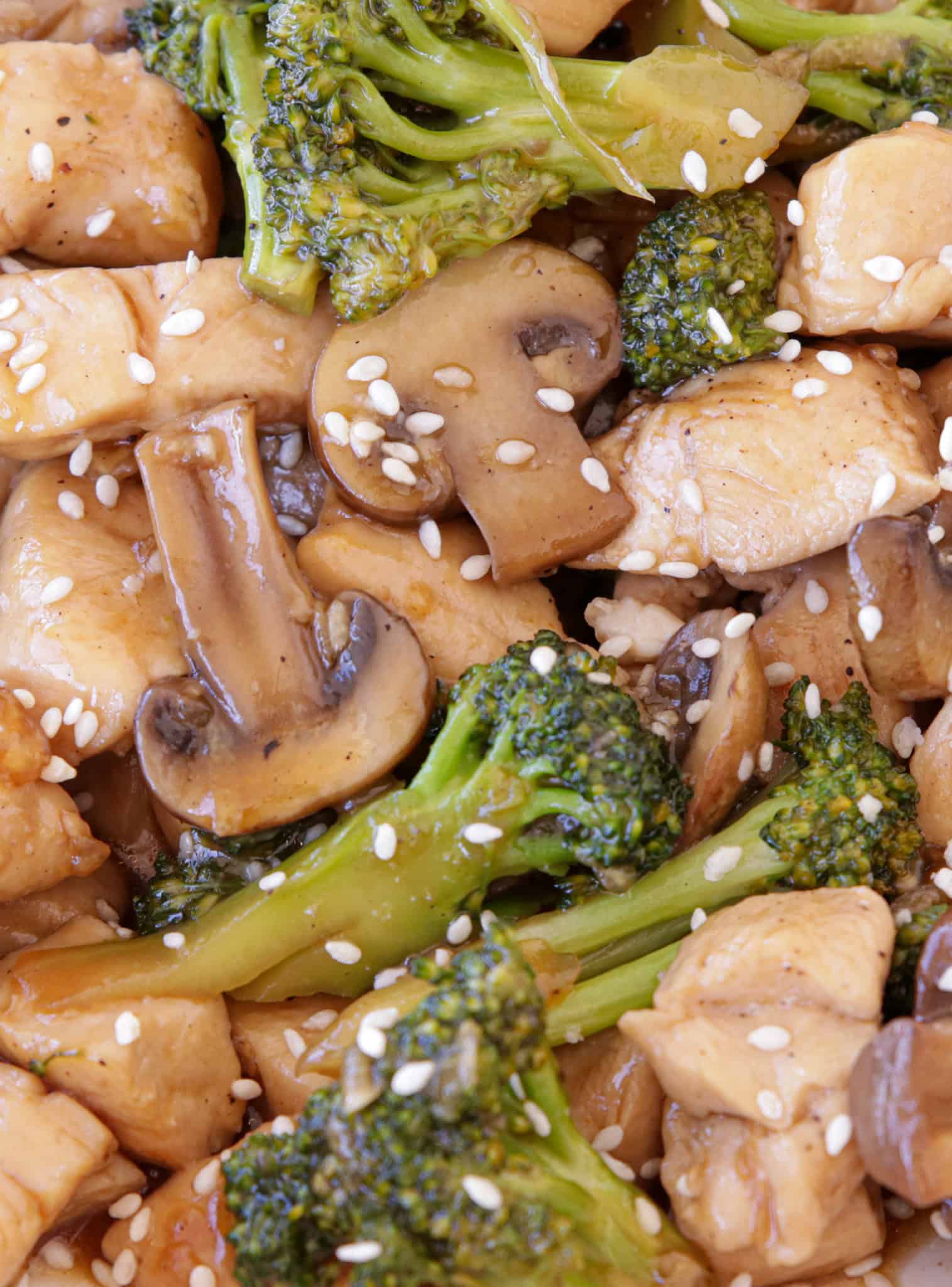 closeup of chicken broccoli mushroom stir fry with sesame seeds.