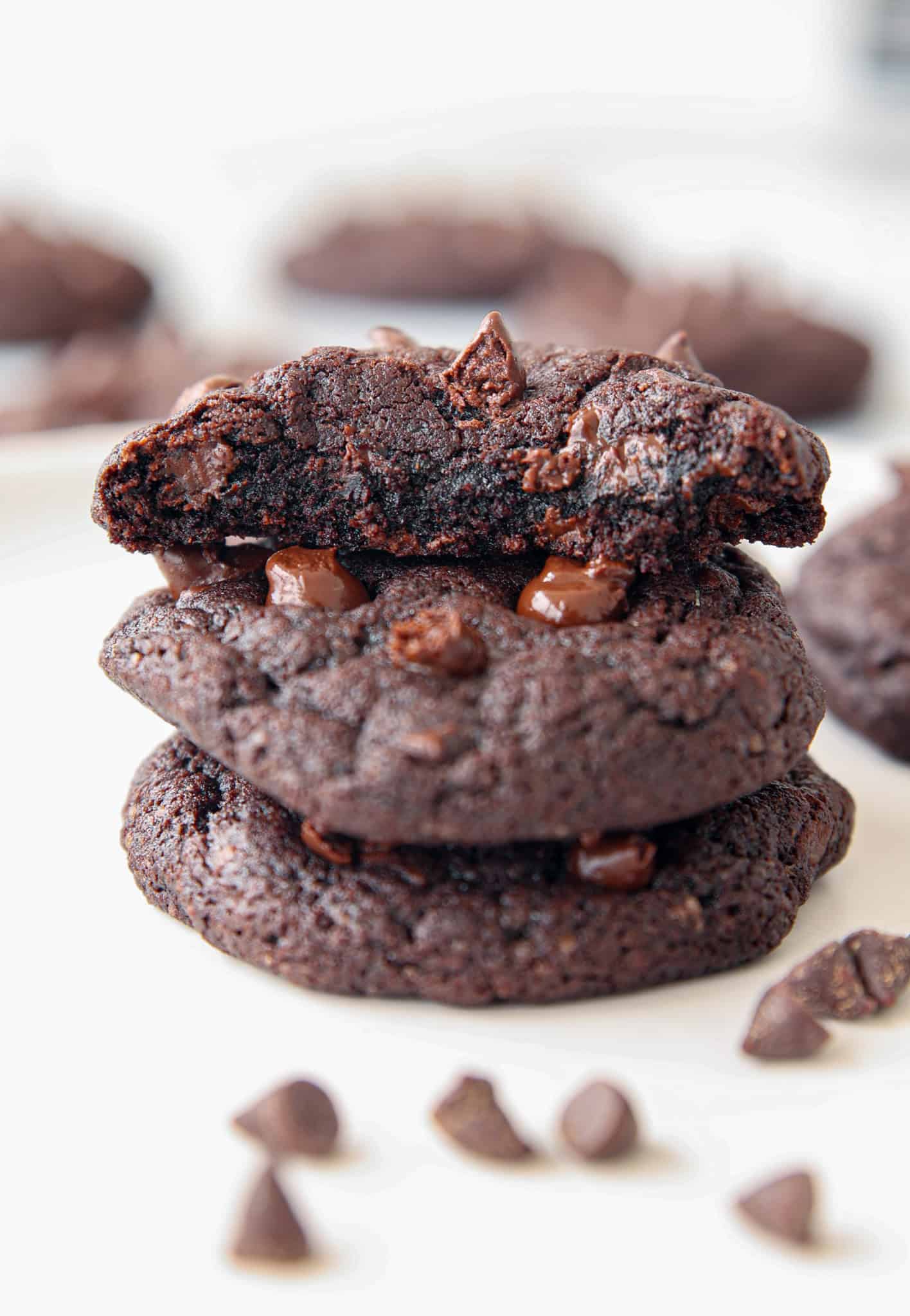 a bitten double chocolate chip cookie on a stack of cookies