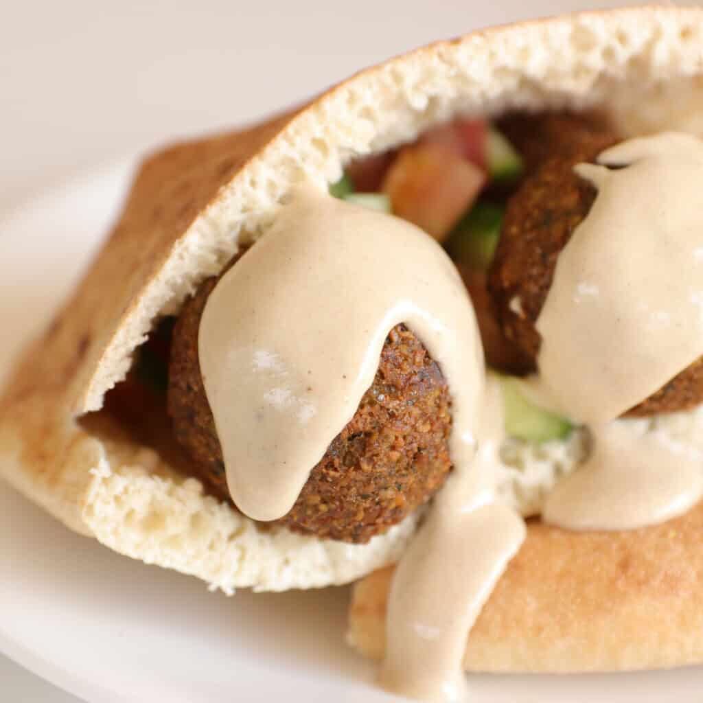 falafel covered in sauce in a pita bread.