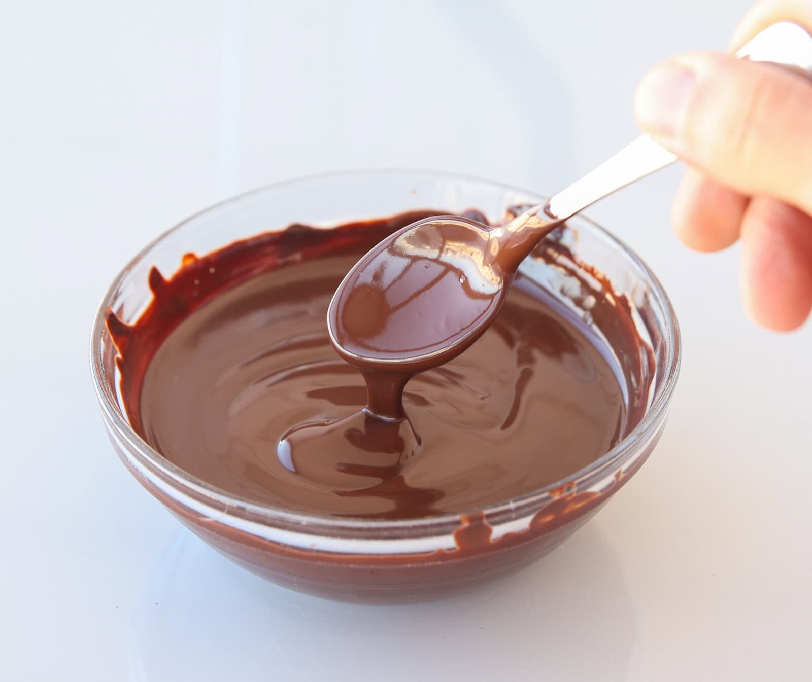 melted dark chocolate dripping from a teaspoon to a bowl