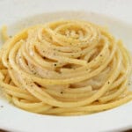 creamy homemade Cacio e Pepe with pecorino cheese on a white plate