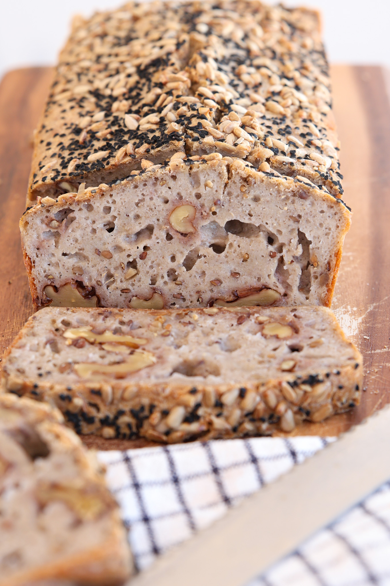 buckwheat loaf on a wood cutting board with a knife and towel