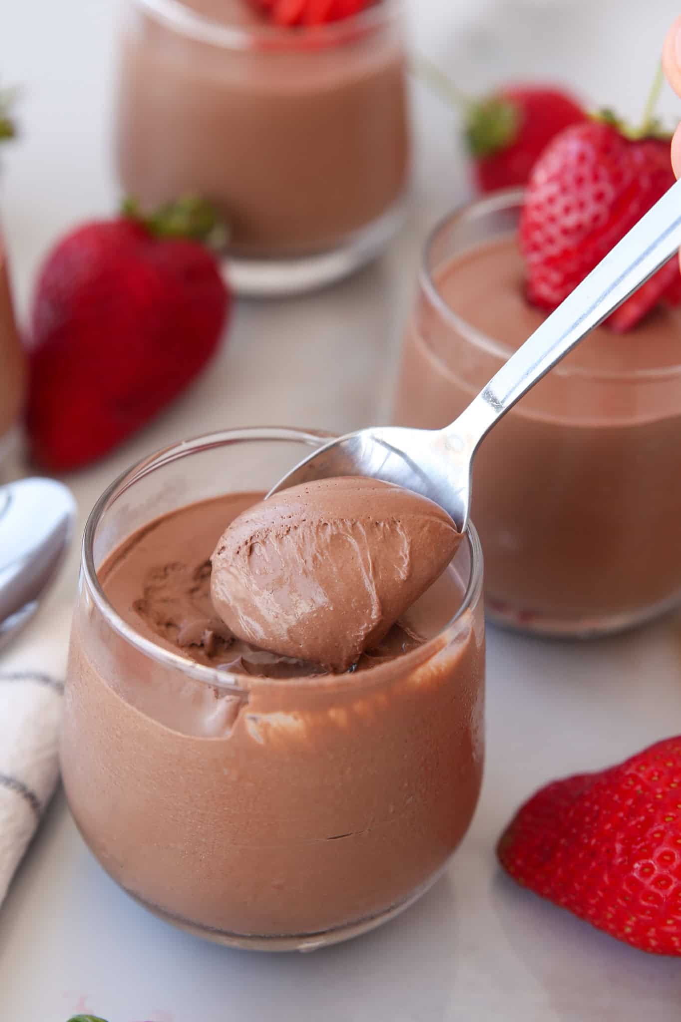 a teaspoon holding a cottage cheese mousse over a glass of creamy mousse