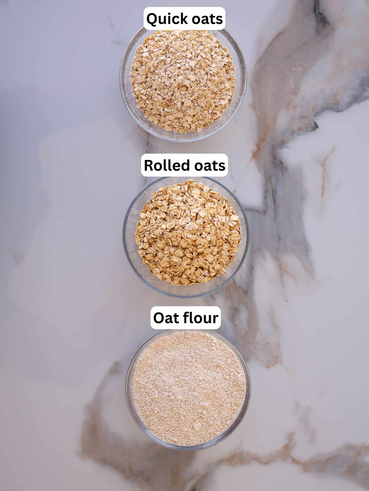 Three glass bowls on a marble surface, each labeled from top to bottom: "Quick oats," "Rolled oats," and "Oat flour," displaying the different textures of each oat product.