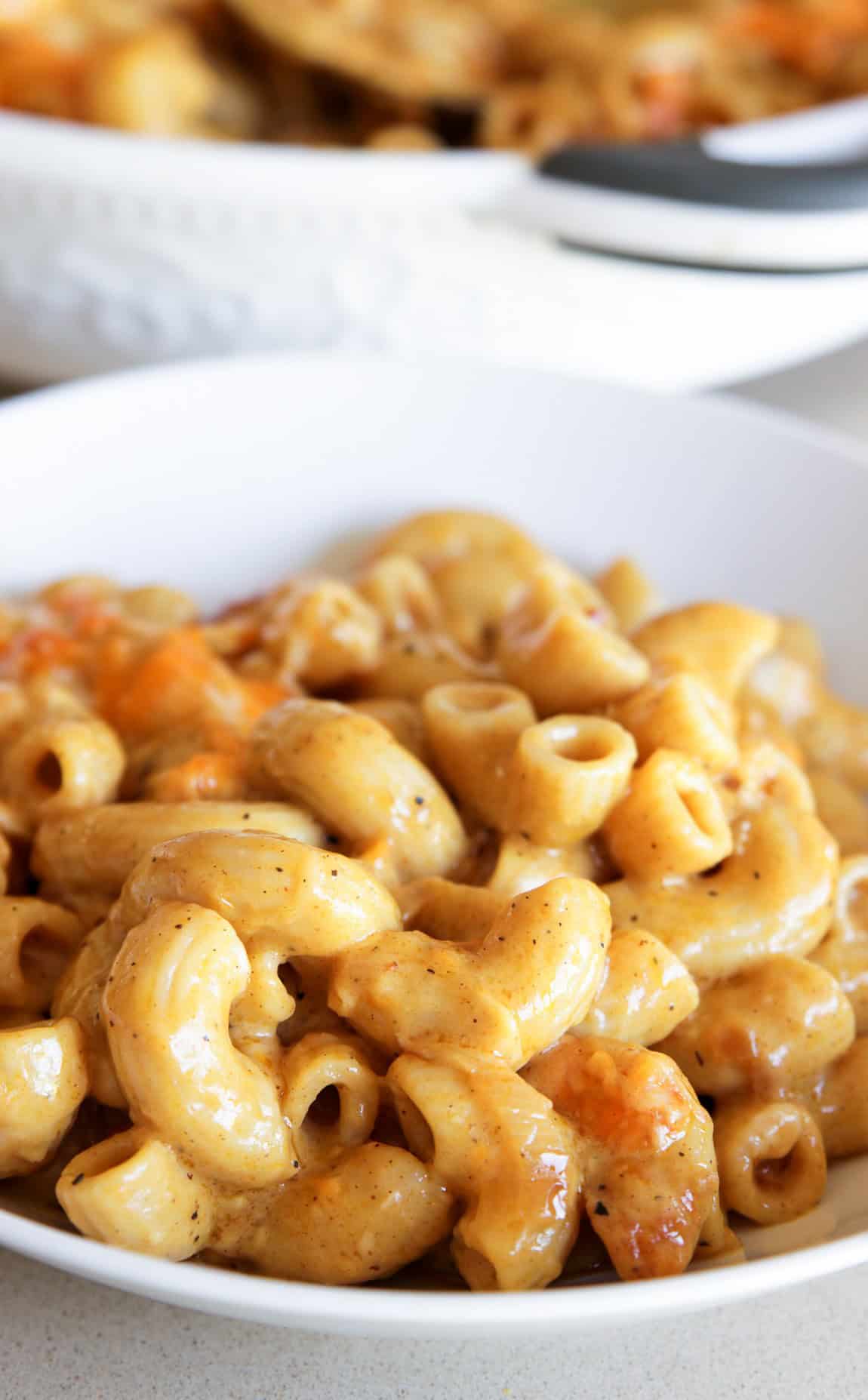 A close-up of a bowl filled with creamy baked curry macaroni and cheese, featuring elbow pasta coated in a rich cheese sauce with hints of browned cheese on top.
