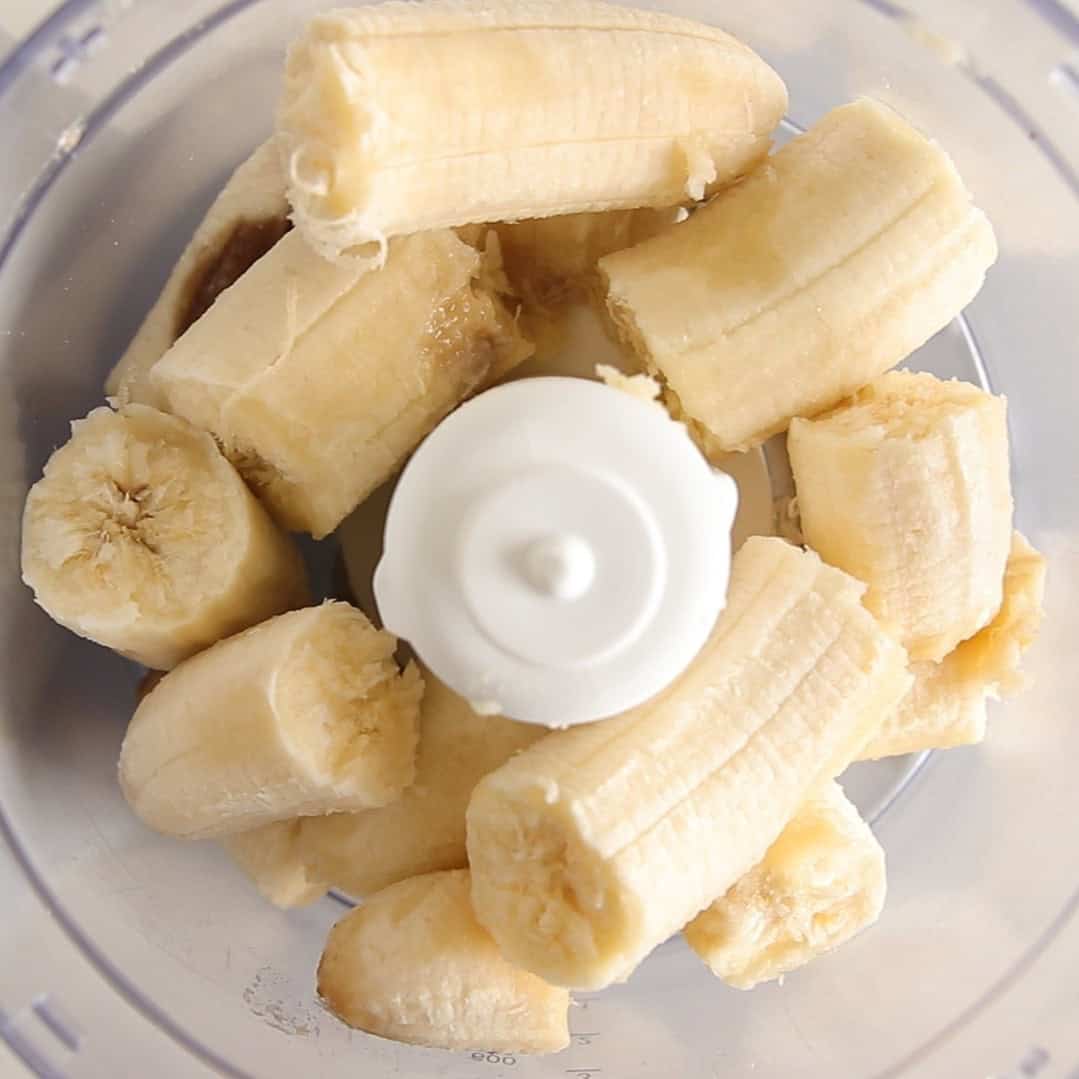 Chunks of peeled banana are placed inside a food processor bowl, ready to be blended.