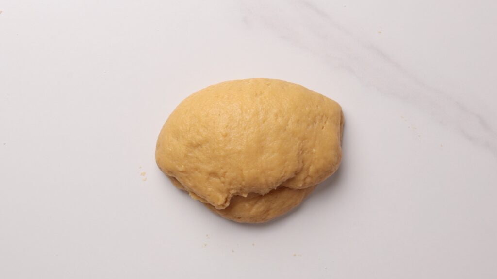 A ball of raw dough rests on a light, marble-patterned surface.