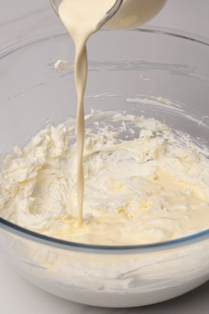 Cream is being poured into a bowl of whipped cream.