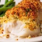 Crispy baked panko-crusted cod fillet with herbs on a white plate.