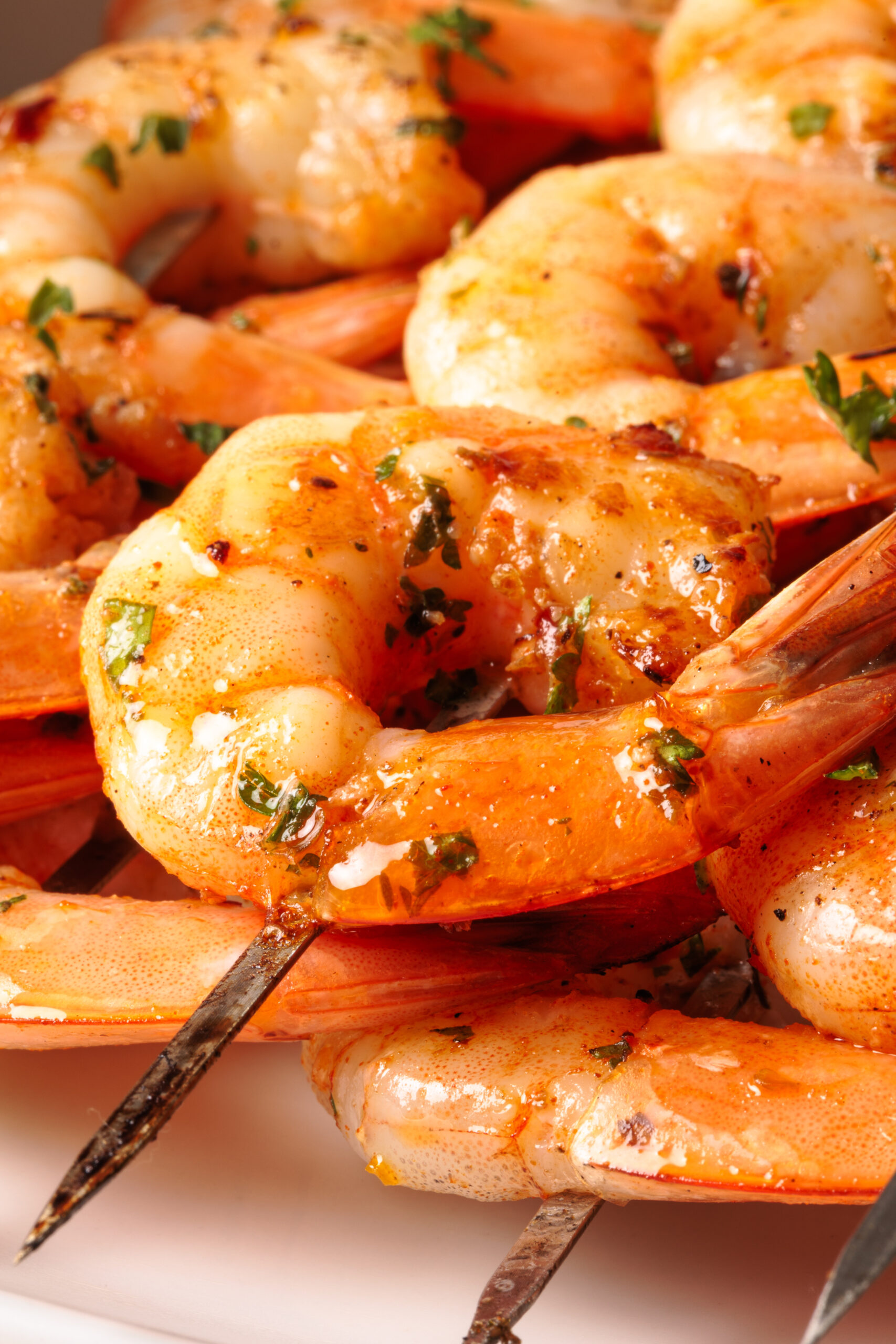 Close-up of grilled and baked  shrimp skewers, seasoned with herbs and spices. The shrimp are cooked and garnished with chopped parsley, giving a fresh and appetizing appearance.