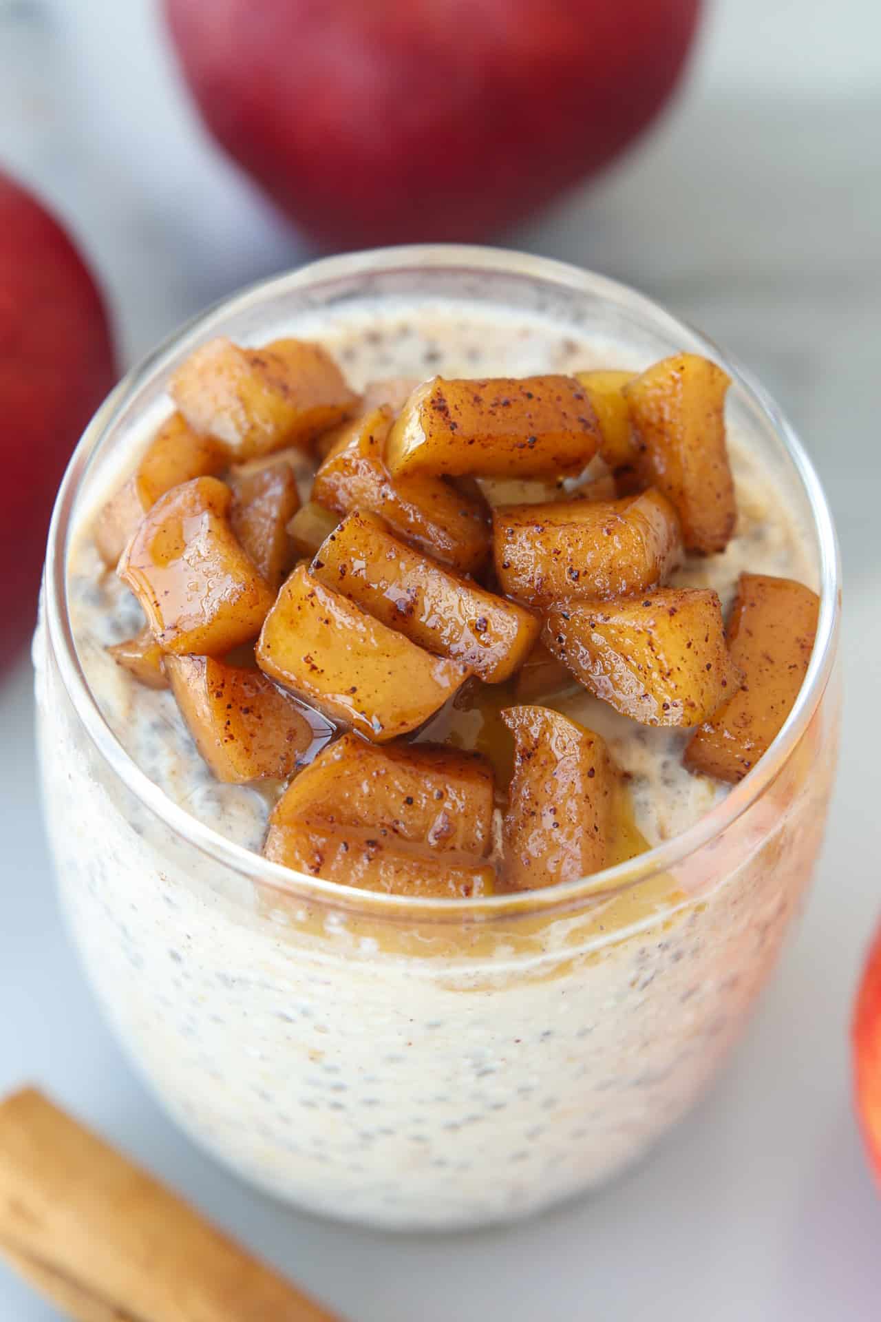 A glass of apple cinnamon overnight oats topped with sautéed cinnamon apples.