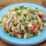 Cauliflower salad with cherry tomatoes and almonds on a blue plate.