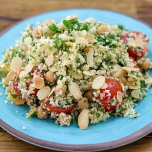 Cauliflower salad with cherry tomatoes and almonds on a blue plate.
