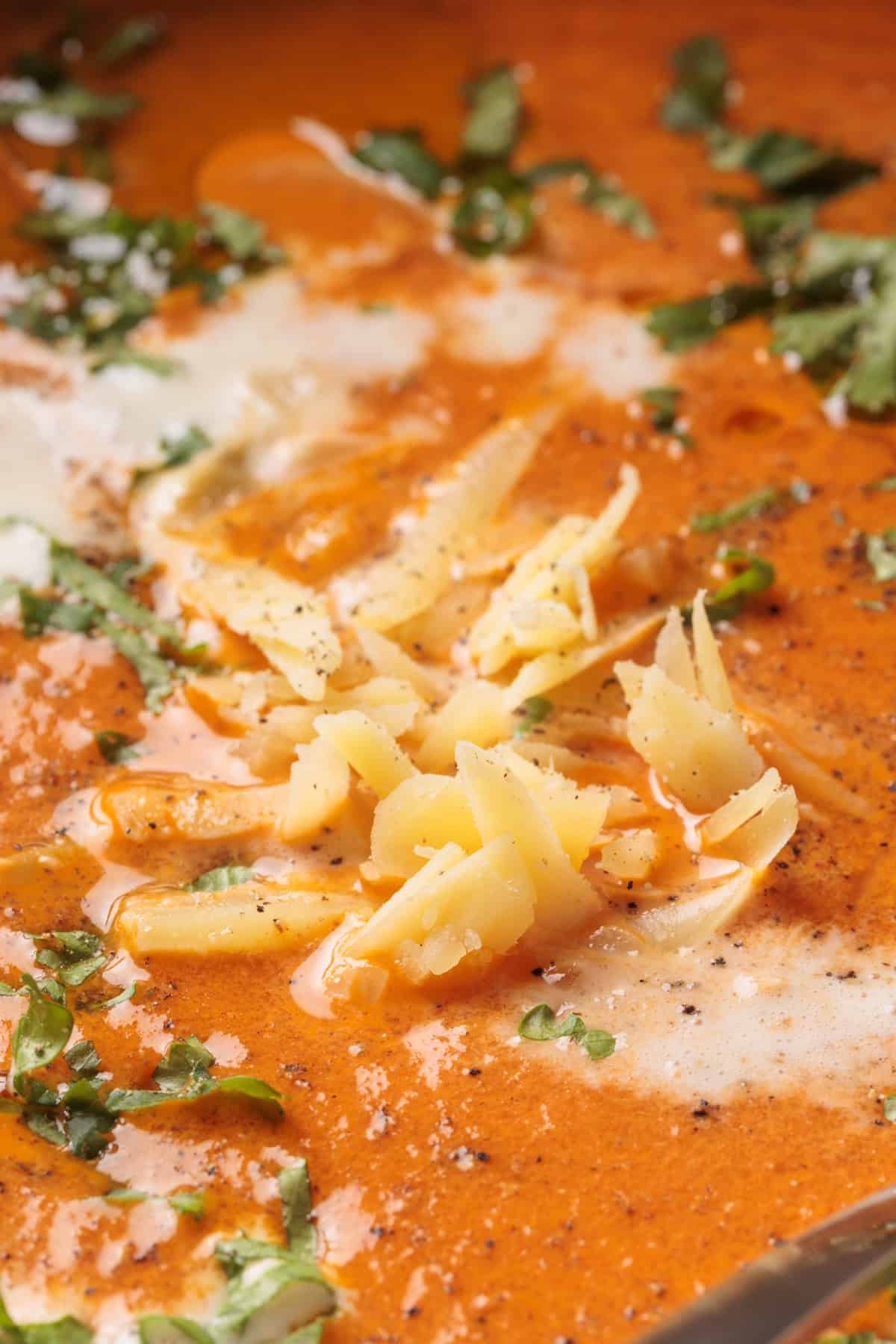 Creamy Roasted red pepper soup with gouda, chopped fresh herbs, and a sprinkle of black pepper.
